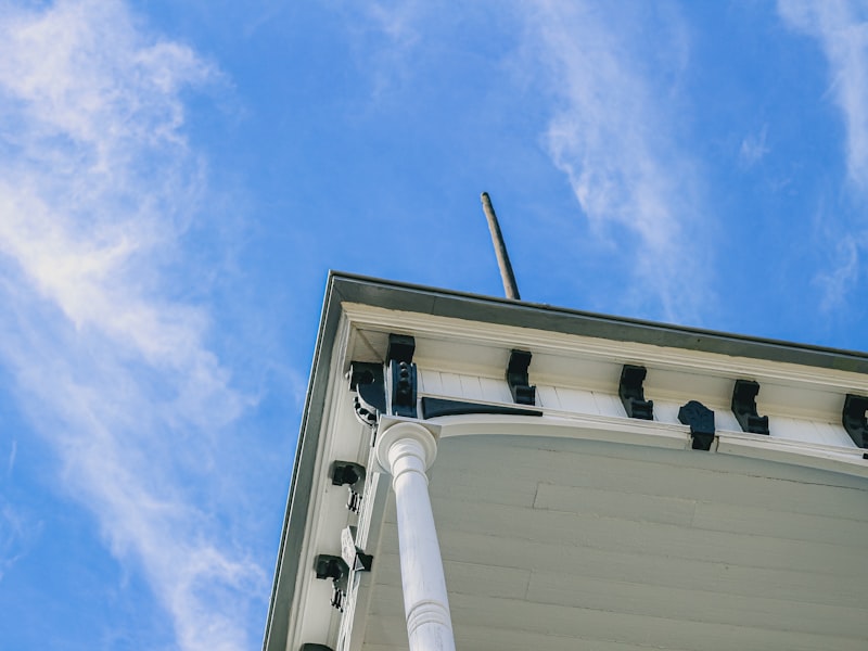 Clean white building eaves and gutter system against blue sky